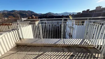Geräumige Terrasse mit Metallgeländer und weitem Blick über die Stadt und die Berge.