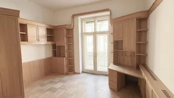 Helles Arbeitszimmer mit maßgefertigten Holzmöbeln, Parkettboden und Zugang zu einem französischen Balkon.