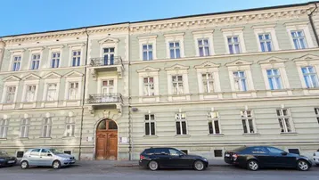 Historische Fassade eines Altbaus mit dekorativen Elementen und kleinen Balkonen an einer Straße.