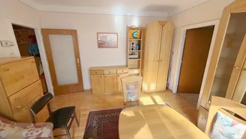 Gemütliches Wohnzimmer mit Holzmöbeln, Parkettboden und Teppich, bietet Platz für Entspannung und Essen.