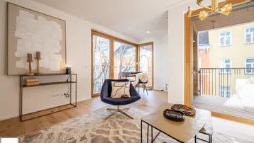 Helles Wohnzimmer mit Holzboden, modernem Mobiliar und Zugang zu einem Balkon.