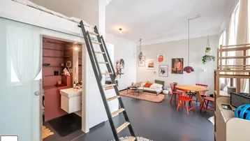 Helles Loft-Apartment mit offenem Wohn-Essbereich, Hochbett und Zugang zu einem kompakten Badezimmer.