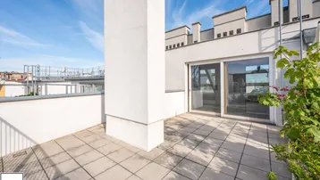 Geräumige Dachterrasse mit hellen Fliesen und Blick auf die Stadt, ideal für Entspannung im Freien.