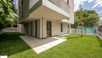 Moderne Wohnanlage mit gepflegtem Rasen und einer kleinen Terrasse im Erdgeschoss.