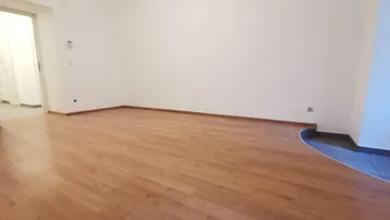 Heller, leerer Raum mit Laminatboden und weiß gestrichenen Wänden, bereit zur individuellen Gestaltung.