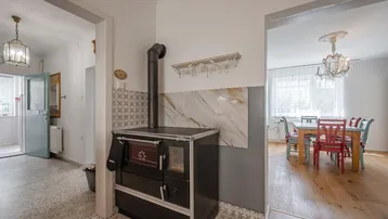 Traditioneller Küchenbereich mit einem Holzofen und Blick auf den angrenzenden Essbereich.