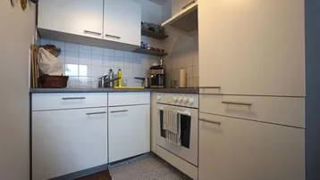 Funktionale Küche mit weißen Schränken, Fliesenrückwand und integrierten Elektrogeräten.