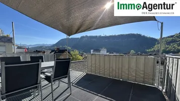 Große Dachterrasse mit Esstisch, Sonnensegel und weitem Blick auf die umliegenden Berge.