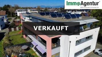 Moderne Wohnanlage mit Flachdach, Solaranlage und Garten in grüner Wohngegend.