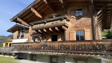Traditionelles Holzchalet mit aufwendig geschnitztem Balkon und alpiner Architektur.