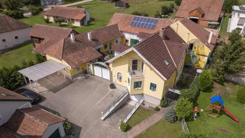 Luftaufnahme eines Anwesens mit mehreren Gebäuden, großem Hof und Spielplatz.
