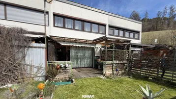Hinteransicht des Hauses mit kleinem Gartenbereich und einer Holzterrasse.