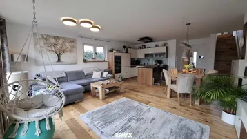 Offener Wohn-Essbereich mit Holzboden, gemütlichem Sofa, Esstisch und integrierter Küche.