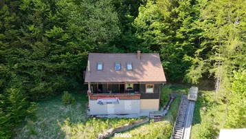 Luftaufnahme eines charmanten Hauses umgeben von dichtem Wald mit einer Seilbahn.