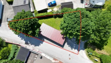 Luftaufnahme des Grundstücks mit roter Umrandung, kleinem Gebäude und viel Grünfläche.