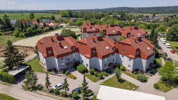 Luftaufnahme einer Wohnanlage mit mehreren Gebäuden und roten Dächern in ländlicher Umgebung.