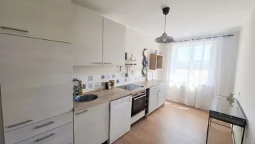 Funktionale Küche mit hellen Holzfronten, integrierten Geräten und einem Fenster.