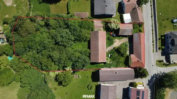Luftaufnahme eines Grundstücks mit Wohnhaus, Nebengebäuden und großem Baumbestand, rot umrandet.