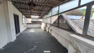 Überdachte Loggia mit Blick ins Grüne, in einem Zustand, der eine Renovierung erfordert.