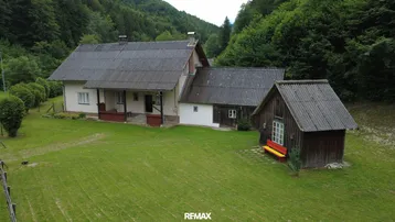 Haus mit großem Garten und Nebengebäude in ländlicher Umgebung.