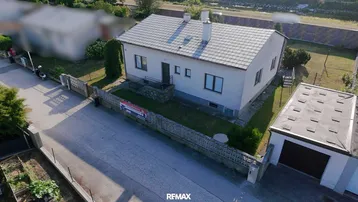 Luftaufnahme eines Einfamilienhauses mit Garage und Gartenbereich von der Straßenseite.