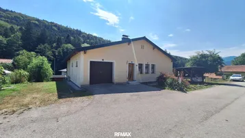 Einfamilienhaus mit Garage und Carport in ländlicher Umgebung mit Bergblick.