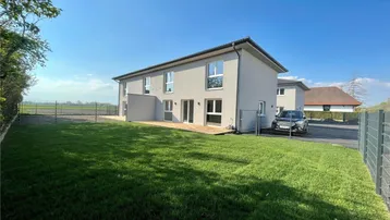 Modernes Einfamilienhaus mit großem Garten, Holzterrasse und weitem Blick ins Grüne.