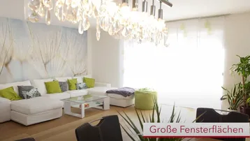 Helles Wohnzimmer mit großem Sofa, modernem Kronleuchter und dekorativer Wandtapete.