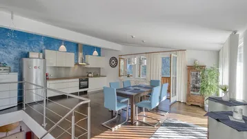 Heller Wohn-Essbereich mit moderner Küche, Holzboden und Zugang zum Balkon.