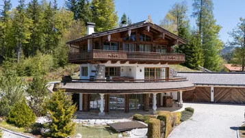 Großzügiges Chalet im alpenländischen Stil mit Holzbalkonen und gepflasterter Auffahrt.