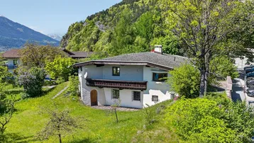 Traditionelles Haus in den Bergen mit üppigem Grün und weitem Blick auf die Landschaft.