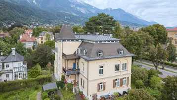 Historische Villa mit eleganter Architektur, umgeben von einem gepflegten Garten und Bergblick.