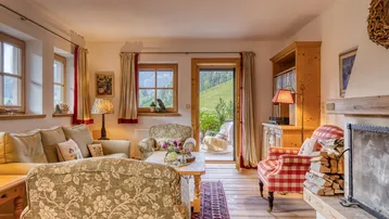 Gemütliches Wohnzimmer im alpinen Stil mit Kamin, Holzboden und Zugang zur Terrasse.