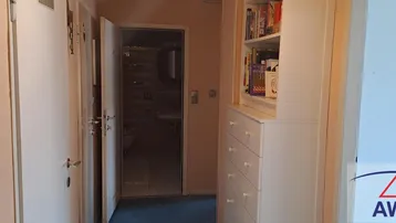 Heller Flur mit Zugang zu einem Badezimmer und einem praktischen Bücherregal.