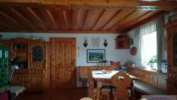 Traditioneller Wohn-Essbereich im alpinen Stil mit viel Holz, Kachelofen und rustikalen Möbeln.