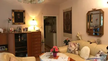 Gemütliches Wohnzimmer mit beigen Sofas, traditioneller Einrichtung und warmem Licht.