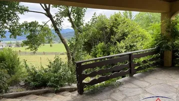 Überdachte Terrasse mit Steinboden und weitem Blick ins Grüne und auf die Landschaft.