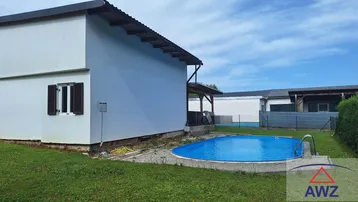 Gepflegter Gartenbereich mit einem Aufstellpool und Rasenfläche neben dem Haus.