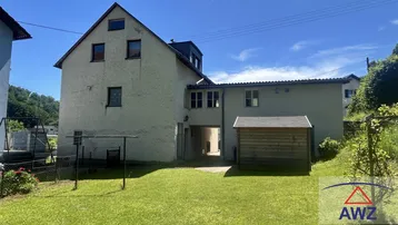 Rückansicht des Hauses mit großem Gartenbereich, Rasenfläche und einem kleinen Holzschuppen.