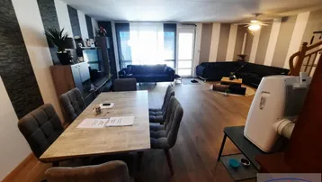 Geräumiger offener Wohn- und Essbereich mit Holzboden und gestreiften Wänden, ideal für geselliges Beisammensein.