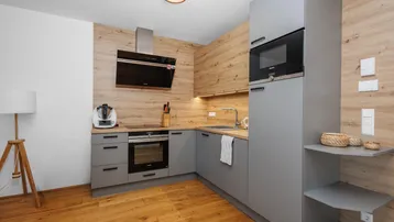 Moderne Einbauküche mit grauen Schränken, Holzakzenten und hochwertigen Geräten.