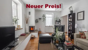 Helles Wohnzimmer mit Holzdielenboden, modernem Kamin und großen Fenstern, das eine gemütliche Atmosphäre schafft.