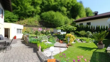 Schöne gepflasterte Terrasse mit Sitzbereich und Blick auf den üppigen, grünen Garten.
