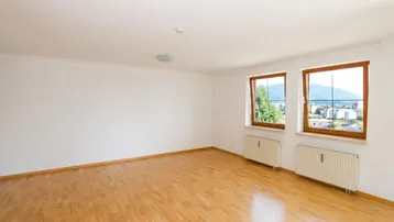Helles, leeres Wohn-Esszimmer mit Parkettboden und Fenstern, die einen weiten Blick bieten.