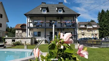 Mehrstöckiges Gebäude mit Balkonen und einem kleinen Pool im gepflegten Gartenbereich.