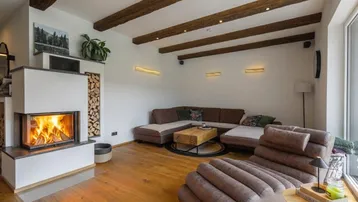 Gemütliches Wohnzimmer mit Kamin, Holzbalken an der Decke und bequemer Sitzecke.