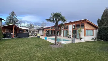 Großzügiger Gartenbereich mit Pool, Palmen und einem modernen Wohnhaus im Hintergrund.