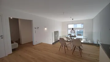 Offener Wohn- und Essbereich mit Glasgeländer, Holzboden und großen Fenstern für viel Licht.