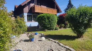 Charmantes Haus mit gepflegtem Garten, Kiesweg und dekorativen Kugelleuchten.