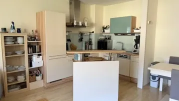 Helle Küche mit Holzboden, integrierter Kücheninsel und offenem Regalbereich.
